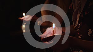 Human palm hands holding burning candle in dark black background. Close up view of burning candle. Concept of spiritual