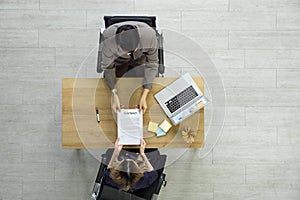 Human Resource Manager in suit handing contract document to young candidate after the interview. Top View