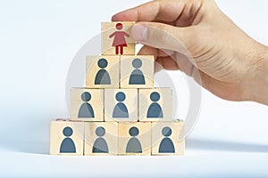 Human resources manager is selecting a female worker atop a pyramid made out of male employee icons