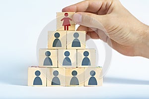 Human resources manager is selecting a female worker atop a pyramid made out of male employee icons photo