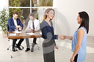 Human resources manager shaking hands with applicant during job interview in offic