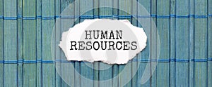 HUMAN RESOURCES text on the piece of paper on the green wood background