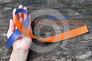 Human rights for family caregivers awareness in orange navy blue fabric ribbon color splashed on human hand old aged background