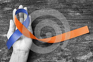Human rights for family caregivers awareness in orange navy blue fabric ribbon color splashed on human hand old aged background