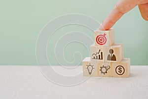 Human`s finger pointed red dartboard icon, top wooden cube, business brainstorming, goal and target concept