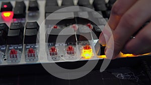 A human's hand assembles the keys of a mechanical keyboard with red switches, close-up shots and in motion