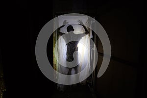 Human silhouette behind packing film in dark creepy room of abandoned building