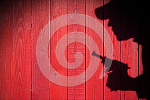 Human silhouette with handgun in shadow on wood background, XXXL