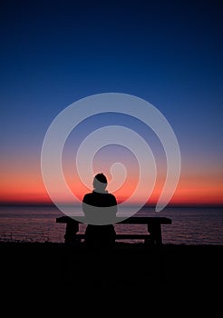 Human silhouette relaxed sitting at table at sea in the sunset time
