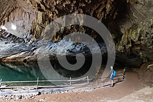 Human silhouette stands inside water cave in Konglor, Laos