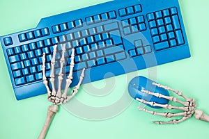 Human skeleton hands typing on blue computer keyboard, flat lay, top view. Social media victim, self isolation, internet addiction