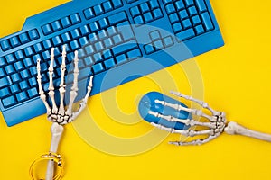 Human skeleton hands typing on blue computer keyboard, flat lay, top view. Social media victim, self isolation, internet addiction