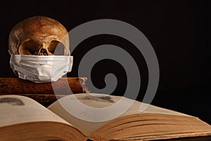 A human skull in a medical mask against the background of the encyclopedia of anatomy