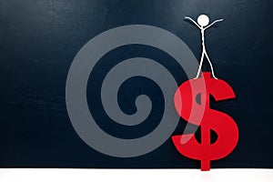 Human stick figure on top of a red dollar sign cutout. Financial success concept.