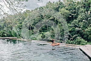 Human swimming in Bali infinity pool