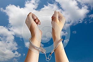 Human trafficking ,slave labor and labor oppression problems concept. two hands was incarcerated by handcuff with blue sky