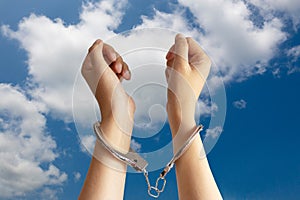 Human trafficking ,slave labor and labor oppression problems concept. two hands was incarcerated by handcuff with blue sky photo