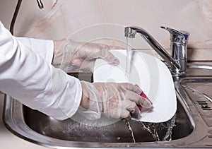 Human washes white plate.  Close up of hand