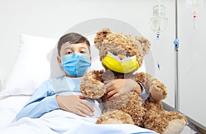 Humanitarian Aid, help for medical protection for Ukraine war, child in hospital bed with teddy bear wearing protective face mask