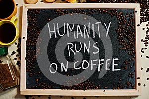 Humanity runs on coffee. Words on blackboard flat lay