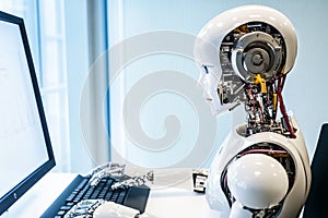 Humanoid robot working on computer using keyboard in office.