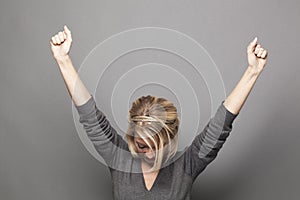 Humble 20s blonde woman raising hands for victory