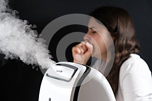 Humidifier and coughing woman in the background. Humidification of the air with cough and viral infections