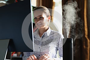 Humidifier with rising steam on desk of office employee