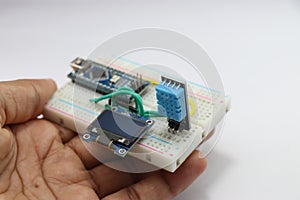 Humidity and temperature sensing module for arduino projects with OLED circuit on a breadboard held in hand showing the concept of