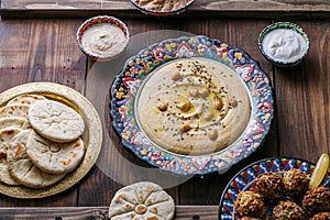 Hummus, chickpea, falafel with tahini, yoghurt and pita in traditional plate