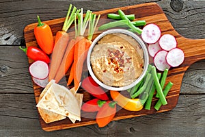 Hummus dip with a platter of vegetables, over wood