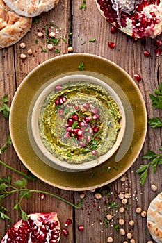 Hummus. Herbal hummus with the addition of pomegranate seeds, parsley, olive oil and aromatic spices in a ceramic pot on a wooden