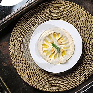 Hummus or hommos, humus with chickpea served in dish isolated on red mat top view on table arabic food