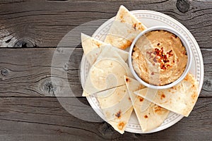 Hummus with pita bread on a plate, above view over wood