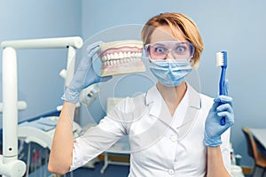 Humor. Dentist holding a human jaw and tooth brush in hand. Funny emotion