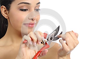 Humorous beautiful woman making manicure with a secateurs photo