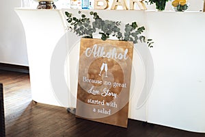 Humorous board about alcohol and love story. White wall background. Wedding day concept.