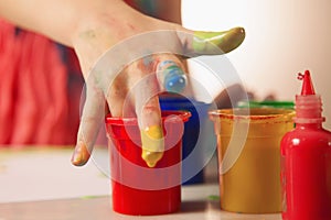 Humorous image of child girl great artist painting a picture with finger. Painting process and education concept