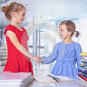 Humorous image of little cute business child girl  handshaking as symbol of good deal, partnership and teamwork