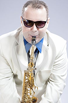 Humorous Male Saxophone Player Performing On Alto Saxo In White Suit and Sunglasses