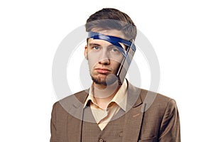 A humorous photo of modern technologies. Young guy with a phone attached to the head using a tape