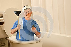 Humorous funny plumber inside toilet with tools and toilet paper