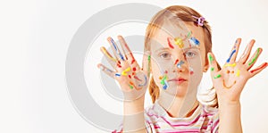 Humorous portrait of little cute girl with children`s makeup and painting colorful hands