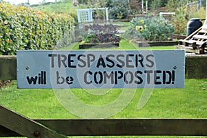 Humorous sign on a five bar gate warning Trespasses will be composted