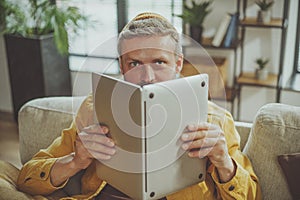 Humorous stock photo concept of bad student who engaged in unproductive studying habits. Guy holding laptop if it were