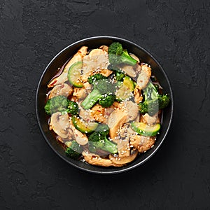 Hunan Chicken in black bowl at dark slate background. Chinese or indo-chinese cuisine takeaway dish