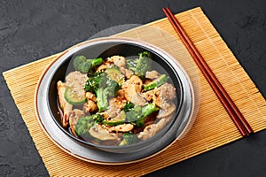 Hunan Chicken in black bowl at dark slate background. Chinese or indo-chinese cuisine takeaway dish