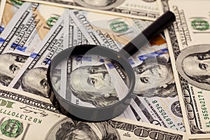 Hundred dollar banknote under magnifying glass