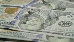 Hundred dollar banknotes with symbols fall on money pile