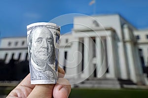 a hundred-dollar bill on the background central bank. Federal Reserve Building in Washington United States